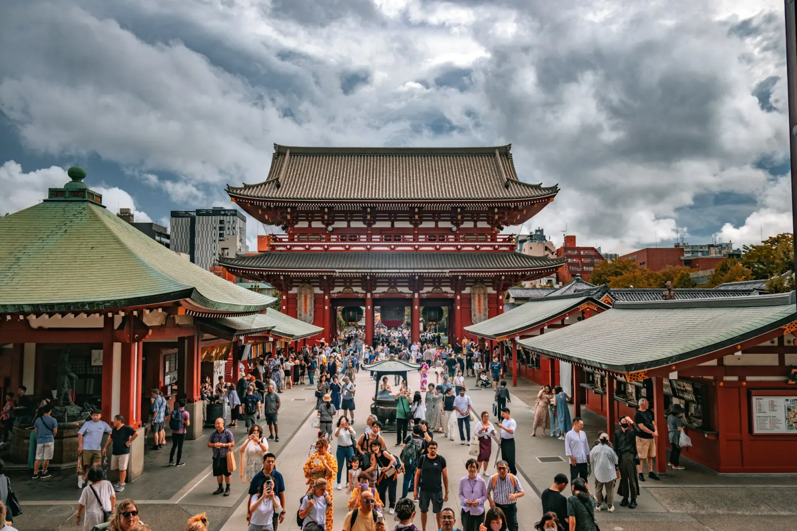Visitors walking toward the red gate of Senso-ji Temple along a shopping street in Asakusa, Tokyo