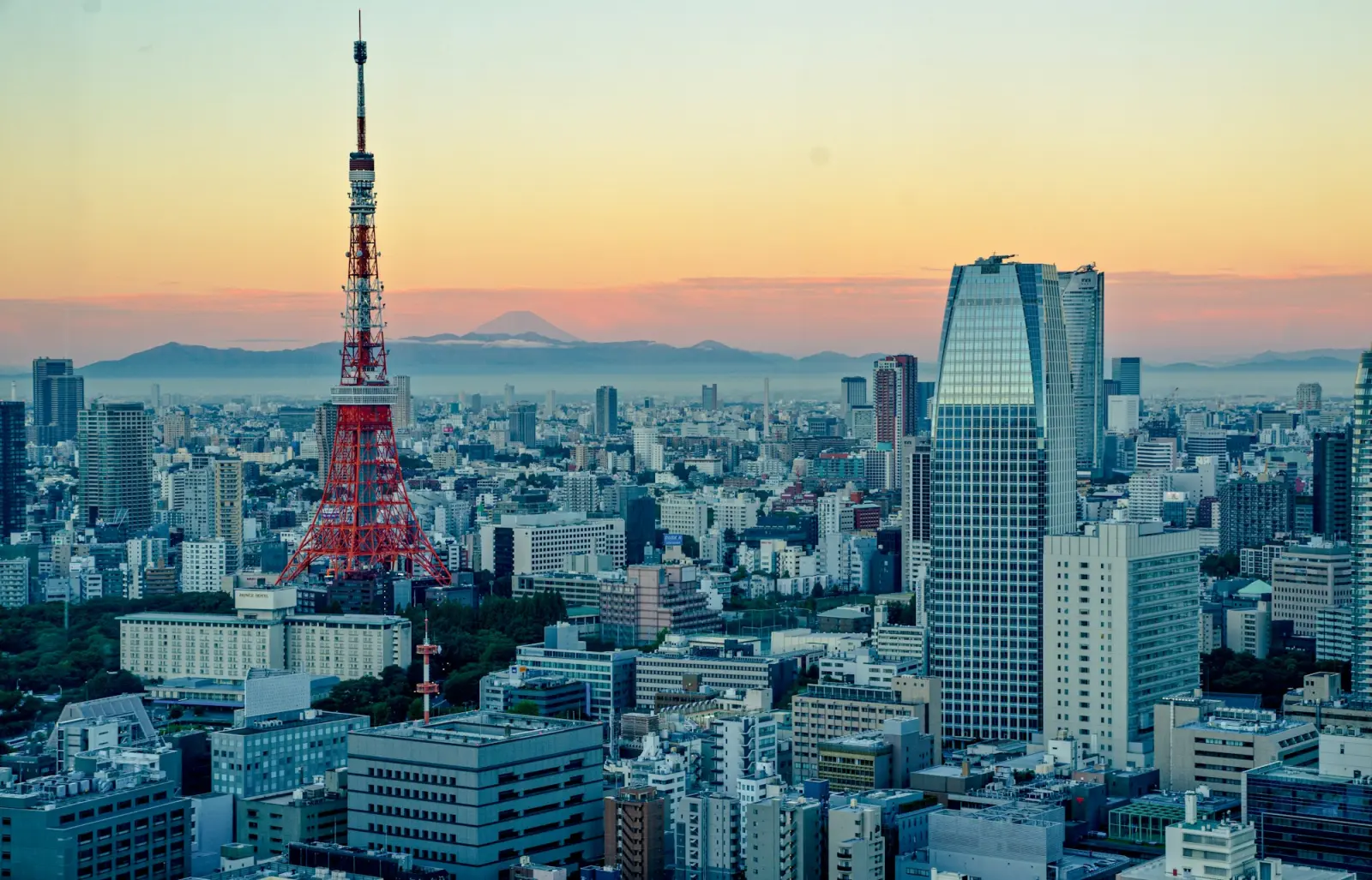 Tokyo Tower rising above the Tokyo skyline under a golden sunset sky