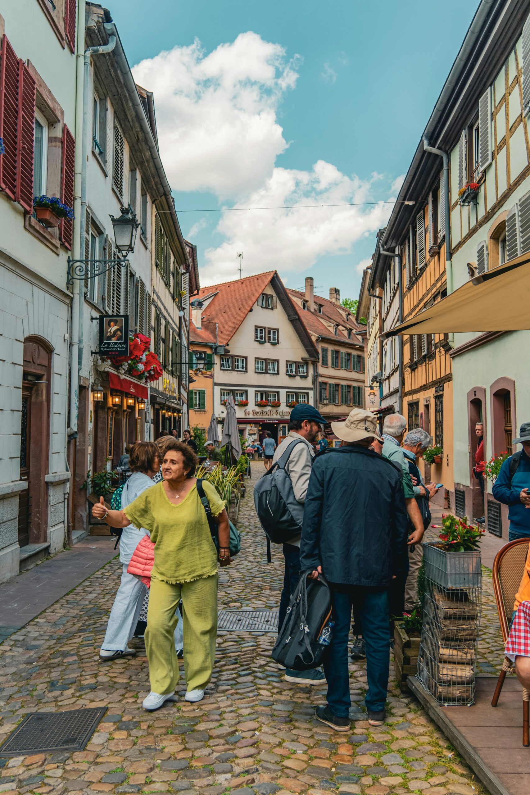 A group of travelers walking down a European cobblestone street lined with historic buildings