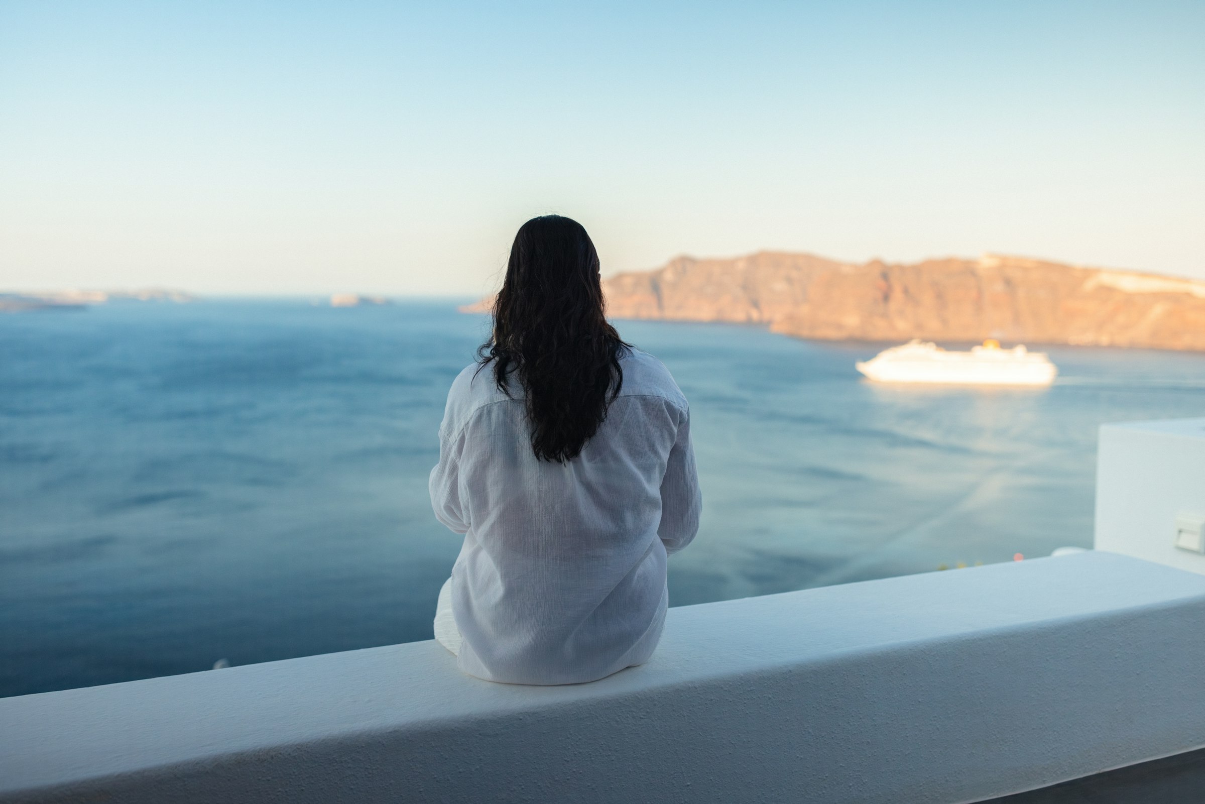 A traveler looking out at the ocean from a cruise ship balcony
