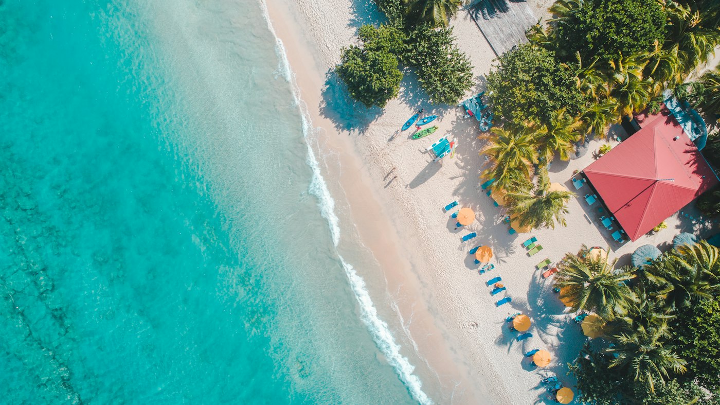 Aerial view of a turquoise Caribbean beach lined with palm trees