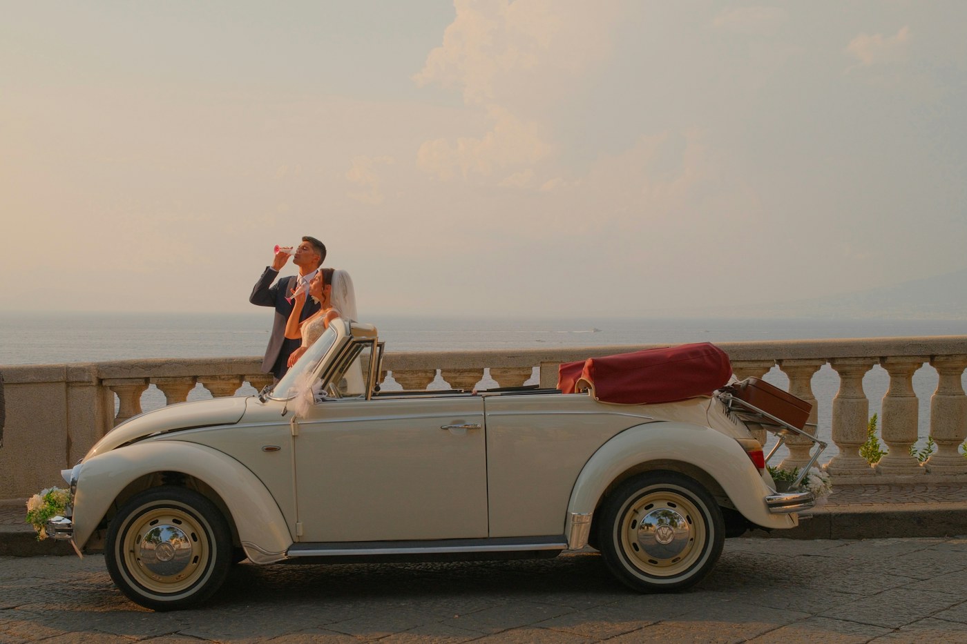 Newlyweds celebrating beside a vintage convertible on the Sorrento coast