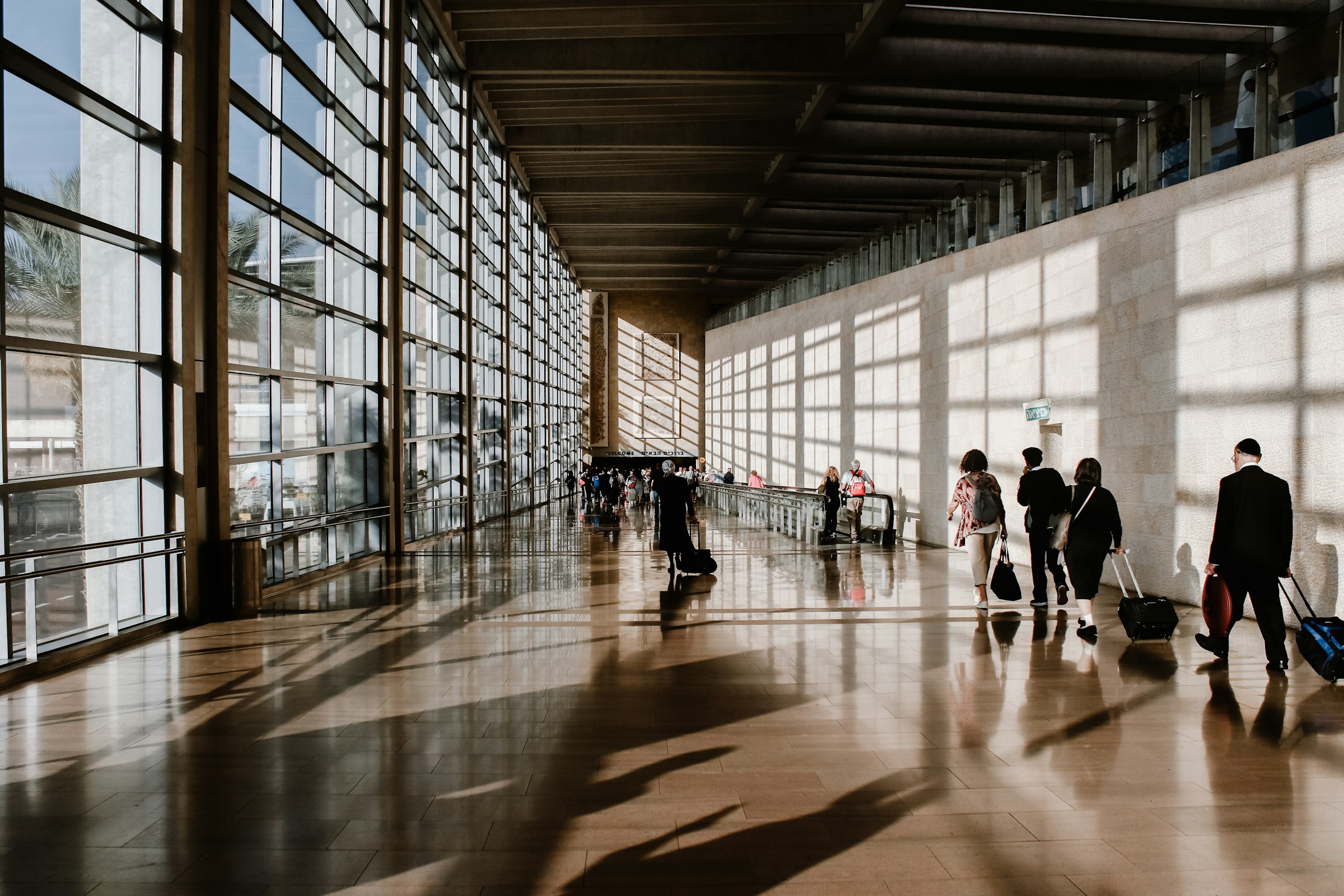 Travelers walking through a sunlit airport terminal